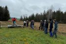 Gruppe Studierender steht auf einer Wiese, ein Landwirt erklärt dabei die Streuwiesenernte