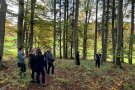 Gruppe Studierender und der Referent im Wald vor einem Biotopbaum