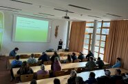 Theresa Singer steht in der Aula vor den Studierenden und hält ihren Vortrag.